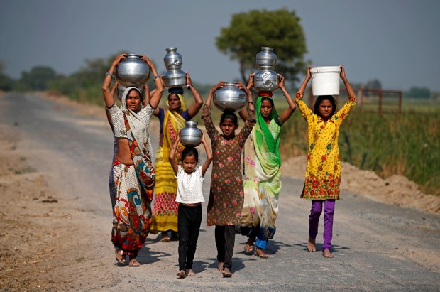 Village women and girls carry water at Fangadi Village on the outskirts of Ahmedabad